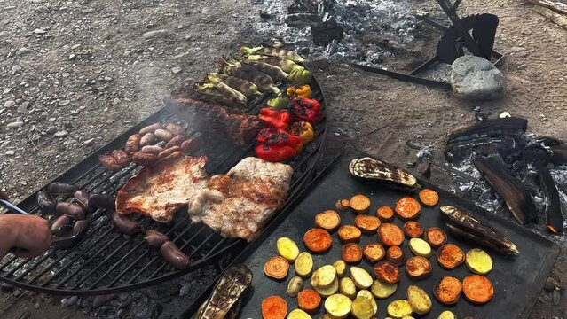 Chef preparing a a delicious grilled vegetables, meat and blood sausages in Argentine grill, south american grilled style. Slow motioan