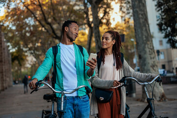 Friends with bicycles using mobile phone outside.