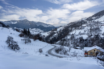 Fototapeta na wymiar Snowy winter day, winding road landscape and clouds.