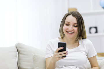 Close-up photo of beautiful pregnant woman looking at the phone.