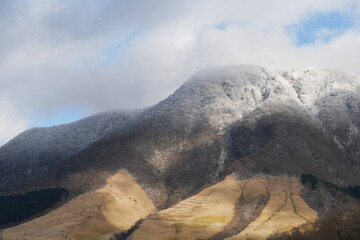 厚い雲と薄い雪に覆われた冬の由布岳
