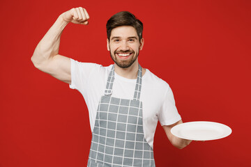 Young waiter strong happy male housewife housekeeper chef cook baker man wear grey apron hold empty...