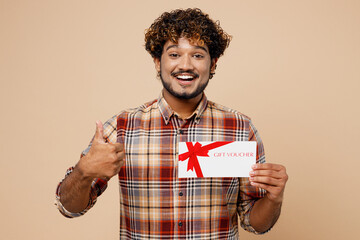 Young overjoyed surprised Indian man wear brown shirt casual clothes hold gift certificate coupon...