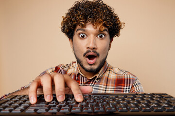 Close up shocked surprised young Indian man in brown shirt casual clothes typing work on pc...