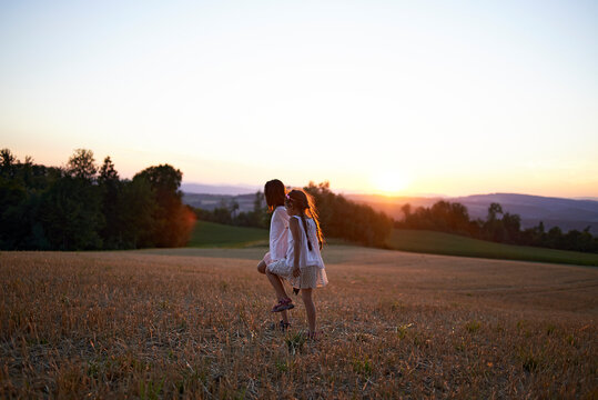 Two young girls walking across a field in summer sunset
