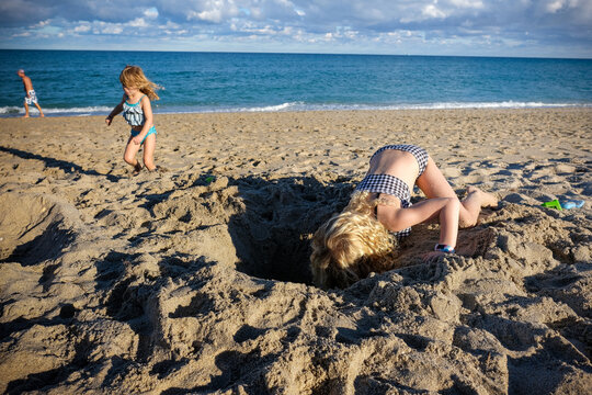 girl digging hole at the beach on a sunny day
