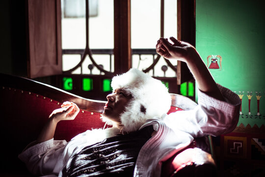 Androgynous woman in alpaca hat sits in window of Spanish colonial fla