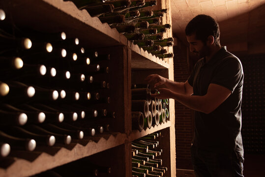 Man stacking sparkling wine bottle in cellar