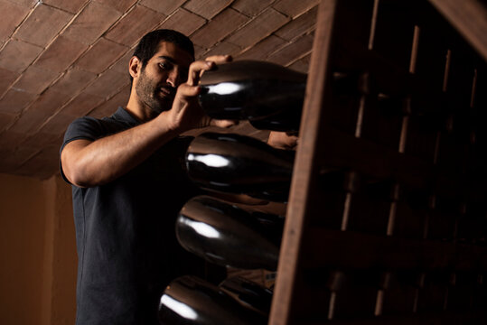 Content man working with bottles in cellar