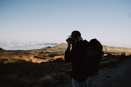 Upper body of a male hiker taking a photo of volcanic landscape