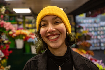 Young woman with smile on face in florist. Worker in flower post.