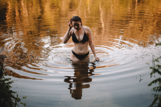 Sensual woman in a bikini walking in river