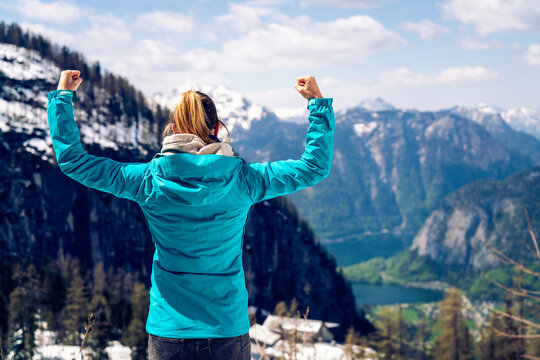 Beautiful young girl on the top of the mountain showing a winnin
