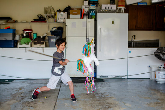 A Happy Child Swings At A Birthday Pinata