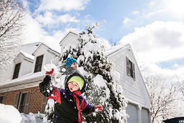boy surrounded by snow getting hit with snowball from behind by boy