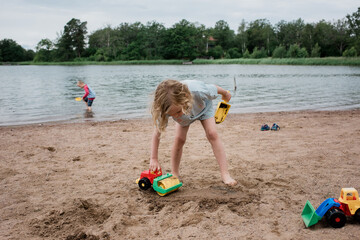 brother and sister playing at the beach with toys in summer