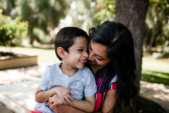 Mother & Autistic Son Smiling & Hugging Under Tree