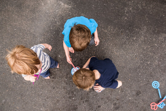 looking down on three boys playing outside with bubbles