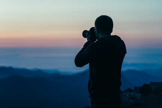 Man taking picture of purple sunset in Washington's National ParkMan t