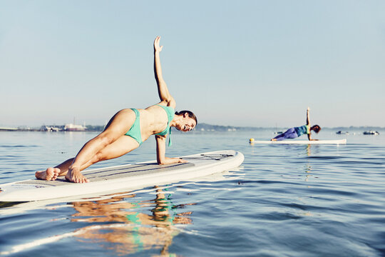 two women on standup paddle boarders doing yoga at sunrise in the fog