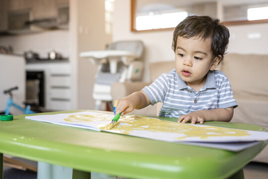Little boy paints with tempera colors paints in her living room