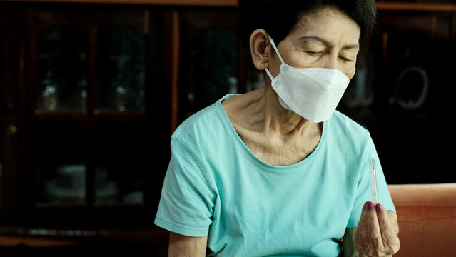 Elderly Woman Who Is Sick Looking At Mercury Thermometer.