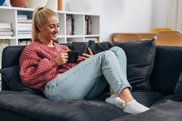 Obraz premium Young blonde woman relaxes on the sofa at home