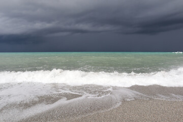 Thunderstorm over a stormy sea, gray clouds in the sky and waves on the sea