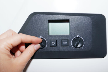 Obraz premium Woman checking settings and temperature on the gas boiler at home.