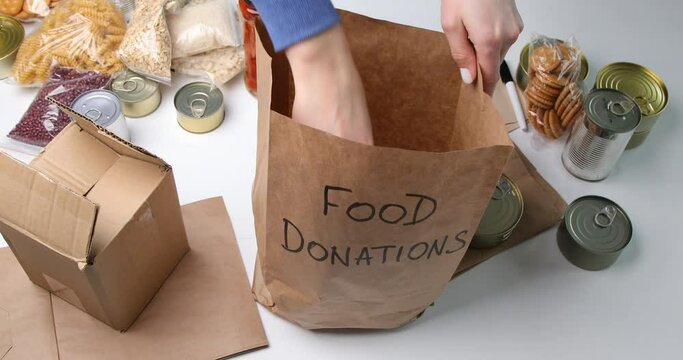 Food donations with pasta, rice, oil, peanut butter, canned food, jam and other  on light background, top view.  Food donations or delivery concept.