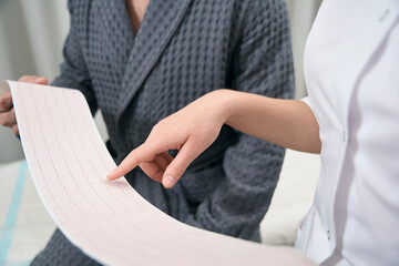 Photo of discussing doctor and patient after the examining heartbeat in hospital