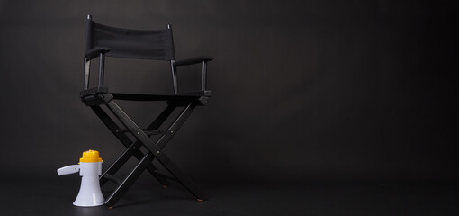 Black Director chair and megaphone on black blackground.