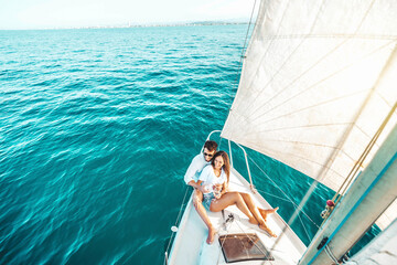 Young couple relaxing on yacht cruise - Two lovers enjoying summer vacation experience on sail boat...