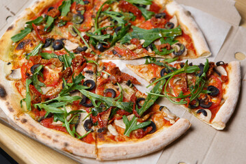 Italian pizza with arugula, tomato sauce, mushrooms and black olives delivered in cardboard box for lunch