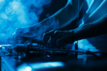 Techno party DJ mixing vinyl records in dark nightclub. Close up photo of disc jockey playing music on stage