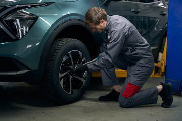 Fototapeta na wymiar Repairman inspecting car wheel in the workshop