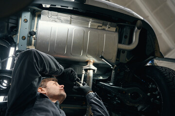 Professional male checking exhaust resonator in the workshop - obrazy, fototapety, plakaty