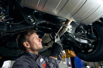 Male checking exhaust resonator in the workshop
