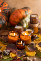 Soy candles burn in glass jars. Tree leaves, pumpkin. Comfort at home. Candle in a brown jar. Scent and light. Scented handmade candle. Aroma therapy. Autumn mood. Cozy home decor in fall.
