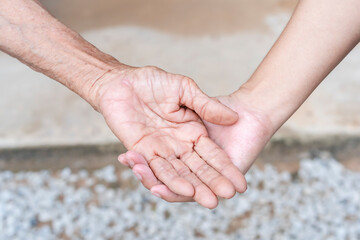 Close-up of old and young holding hands. Middle-aged mommy's wrinkled hands holding young daughters, a millennial woman supporting mature mum, showing care, and love. Support for the elderly concept.