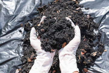 Hands holding abundance soil for agriculture or preparing to plant  Testing soil samples on hands with soil ground background. Dirt quality and farming concept. Selective focus on black soil in front