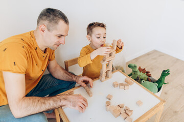 Loving dad and little boy child have fun play build construct with wooden blocks bricks. Father and son concept