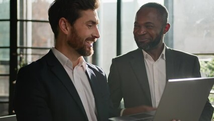 Diverse men partners multiracial colleagues Caucasian man insurance agent consultant adviser and African American investor client with laptop happy satisfied talking online success business in office