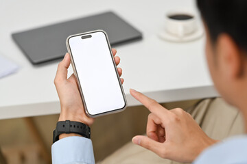 Close up view of man using smartphone at office desk. Blank screen for website design project or graphic display montage