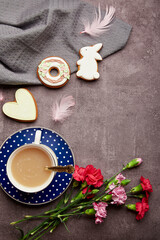 Easter minimalistic coffee time. Glazed cookies, coffee cup, feathers, aster flowers flat. lay. Spring stylish background