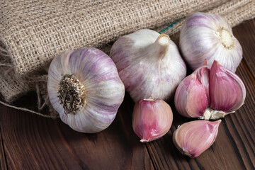 Garlic cloves on wooden table and sackcloth. Fresh peeled garlics and bulbs.