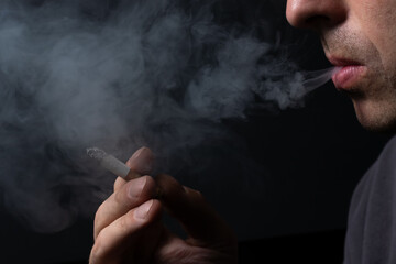 Smoking cigarette in the hand of young man close up