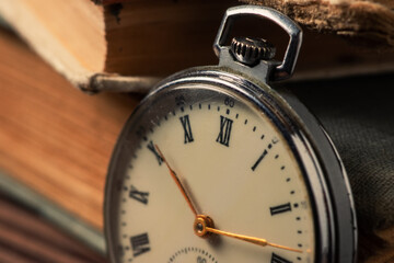 Vintage pocket watch on the background of old books