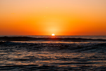 Sunrise from ocean horizon with clear sky.