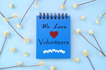 We love volunteers message on blue notepad with minimalist natural design.